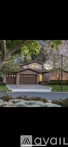 A house with a brown garage door is surrounded by greenery.