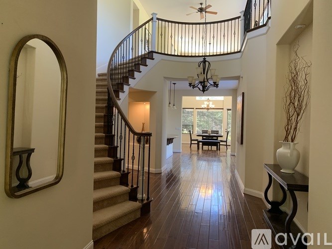 A spacious hallway with a staircase and a chandelier.