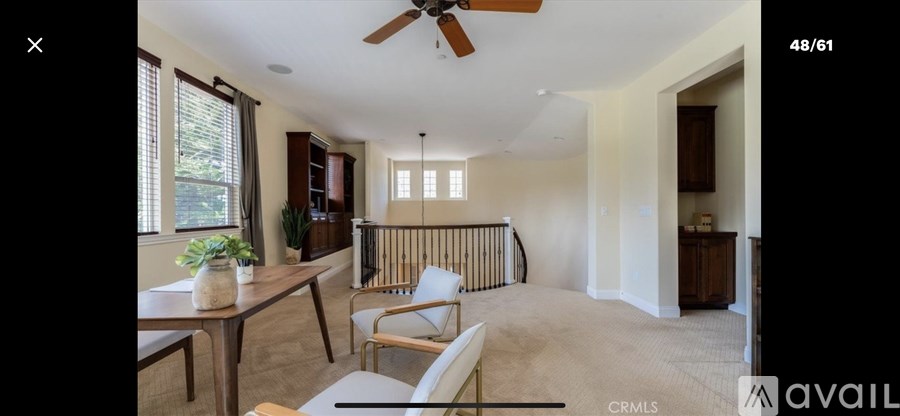 A living room with a ceiling fan and a dining table with chairs.