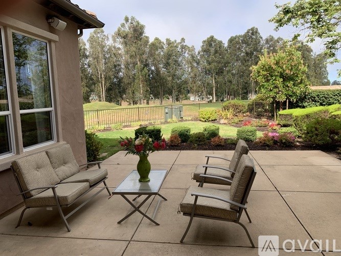 A patio with a table and chairs and a vase of flowers.