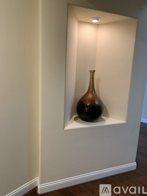 A brown vase sits on a shelf in a room.