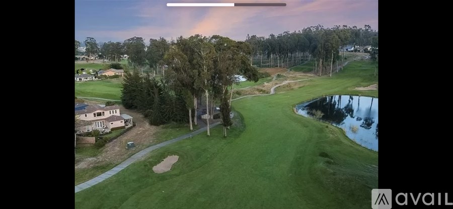 A golf course with a pond and a rainbow in the sky.