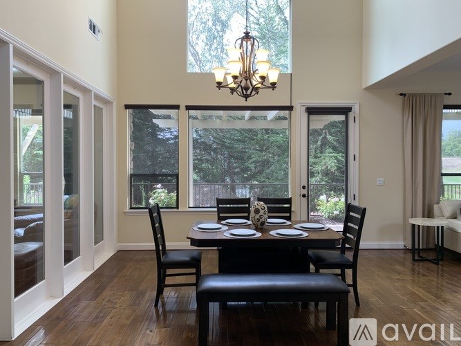 A dining room with a table set for four and a chandelier.