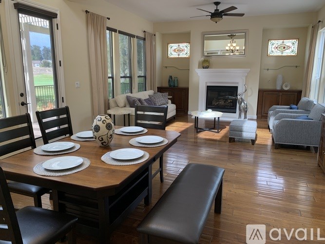 A dining room with a table set for six with a view of a green field.