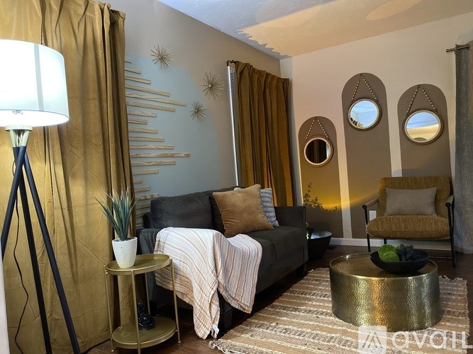 A living room with a grey couch, a gold side table, and a gold floor lamp.