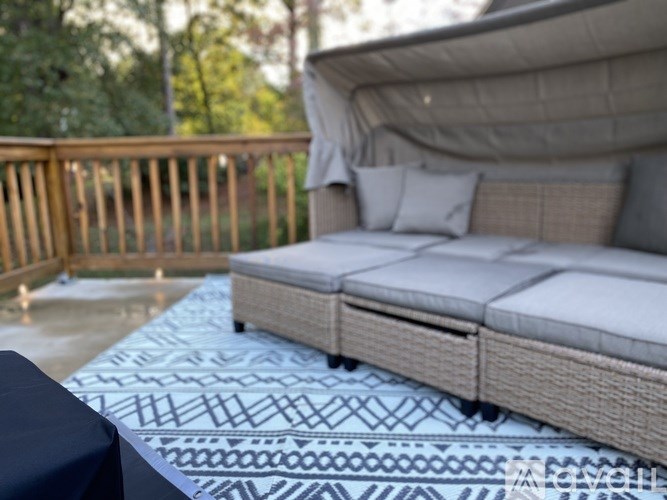 A wicker bed with a blue and white patterned cover is on a wooden deck.