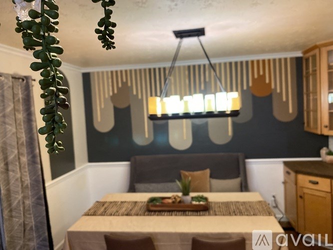 A modern bedroom with a bed, a plant, and a hanging light fixture.
