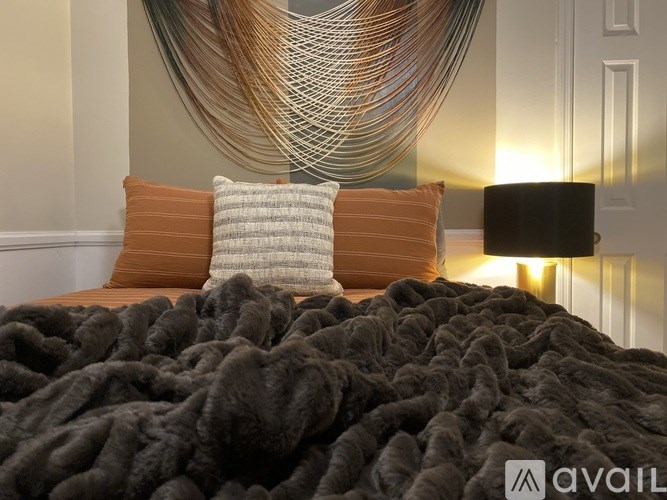 A bed with a grey blanket and orange pillows.