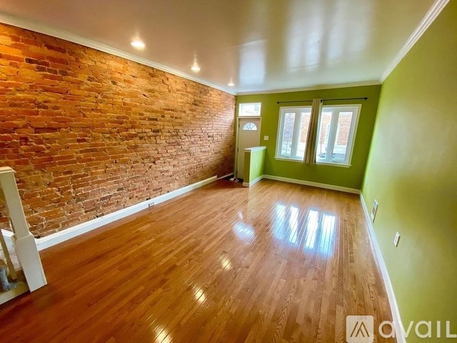 A room with a red brick wall and wooden flooring.