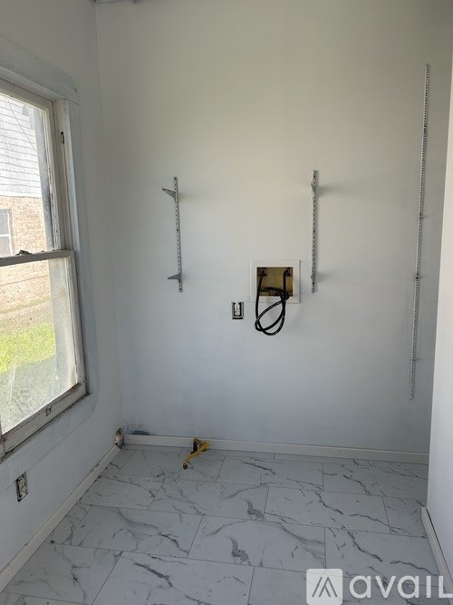 A room with white walls and marble flooring with tools on the floor.