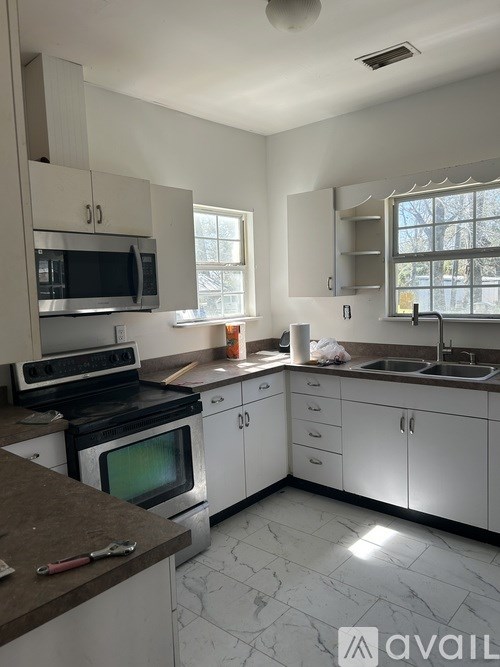 A kitchen with white cabinets and a black stove top oven.