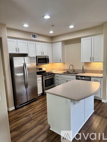 A kitchen with white cabinets and a stainless steel refrigerator.