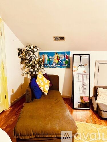 A living room with a brown couch and a painting on the wall.