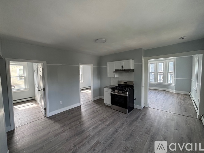 A spacious living room with a kitchen area in the background.