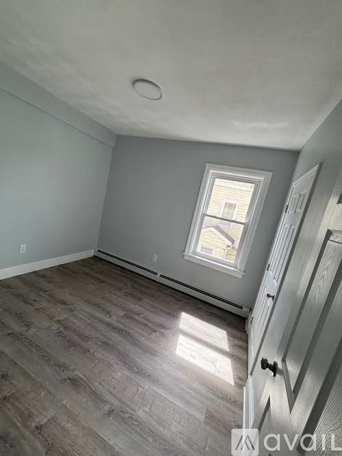 A room with a window and wooden flooring.