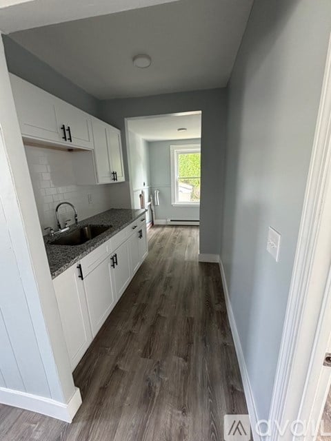 A kitchen with white cabinets and a grey floor.