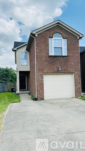 A two-story brick house with a garage door and a window above it.