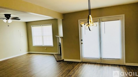 A room with a ceiling fan and sliding glass doors.