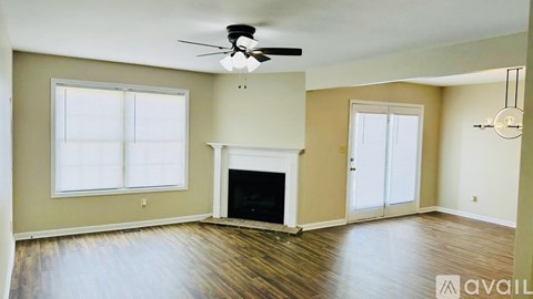 A spacious living room with a fireplace and a ceiling fan.
