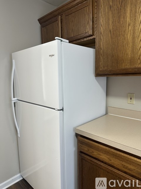 A white fridge in a kitchen with wooden cabinets.