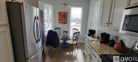 A kitchen with a refrigerator, a stove, and a dining table with chairs.