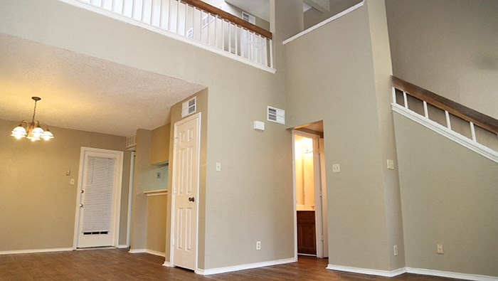 an empty living room with a staircase in the background