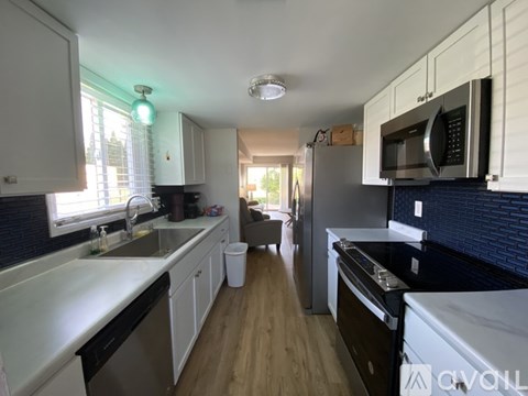 A kitchen with white cabinets and a black countertop.