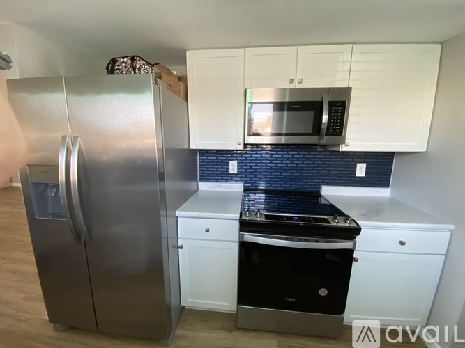 A kitchen with a stainless steel refrigerator and white cabinets.