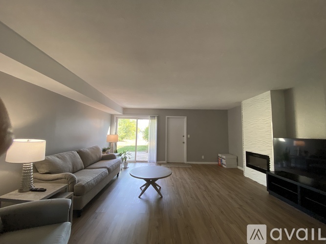 A living room with a grey couch, a wooden coffee table, and a television.