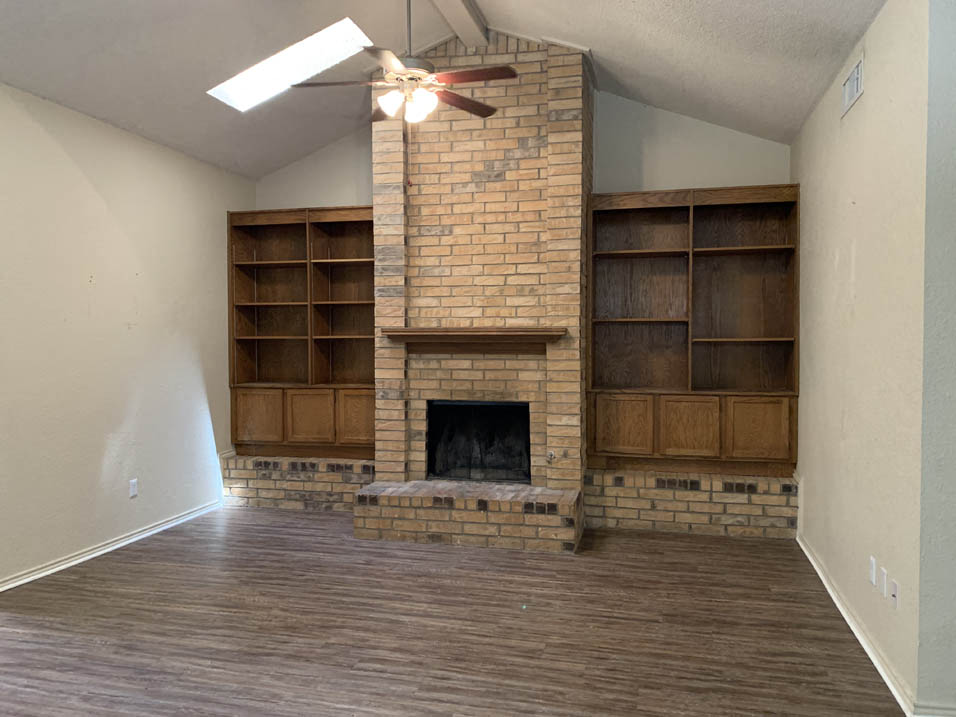 a living room with a brick fireplace and a ceiling fan