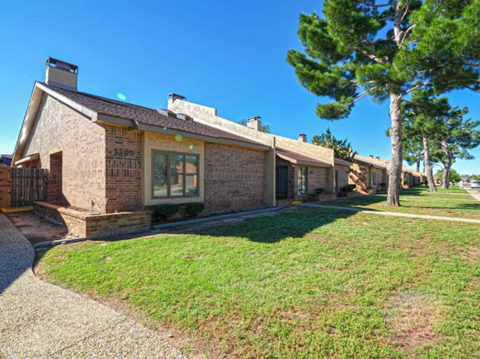 the front of a brick house with a lawn and trees