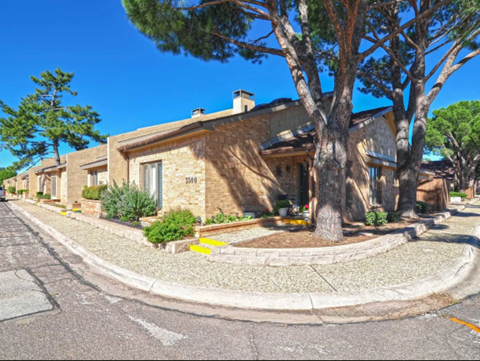 a house with trees and a street in front of it