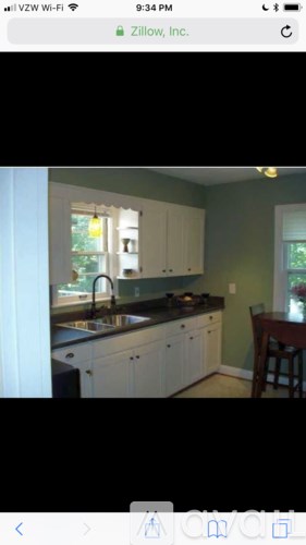A kitchen with white cabinets and a dark countertop.