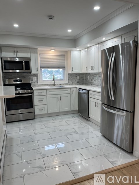 A modern kitchen with a stainless steel refrigerator and white cabinets.