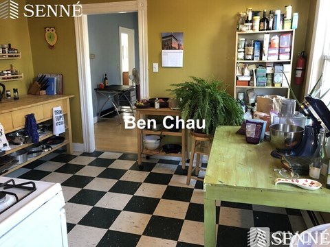 A kitchen with a checkered floor and a table with a bowl and a spoon on it.
