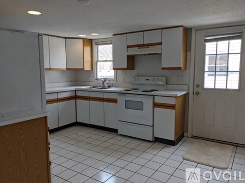 A kitchen with white cabinets and a white stove top oven.