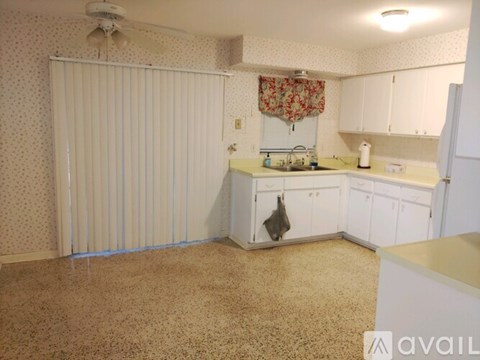A kitchen with white cabinets and a beige carpet.