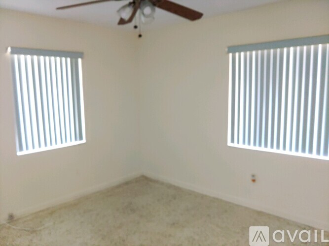 A room with a ceiling fan and two windows.