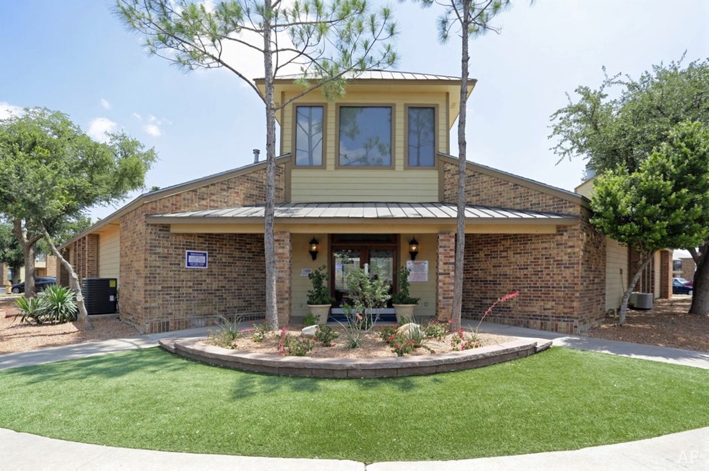 the front of a brick house with a lawn and trees