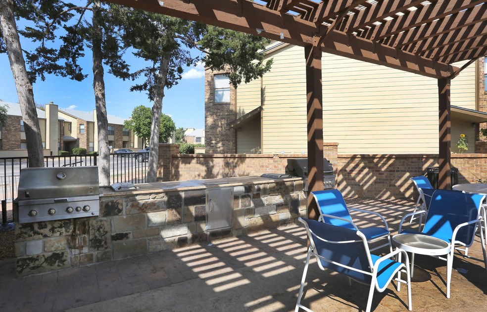 a patio with chairs and a grill and a table