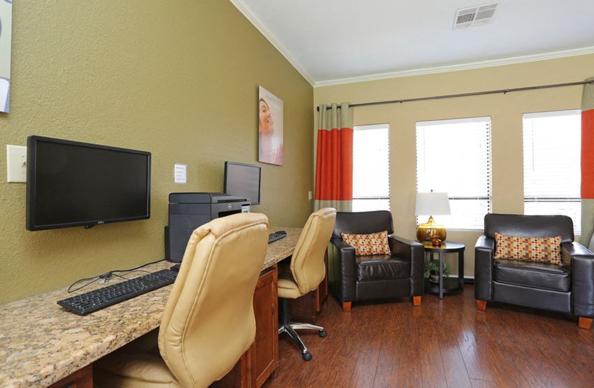a home office with a computer and a desk with chairs