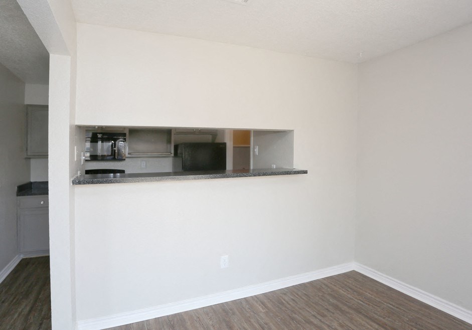 an empty living room with a counter and a kitchen
