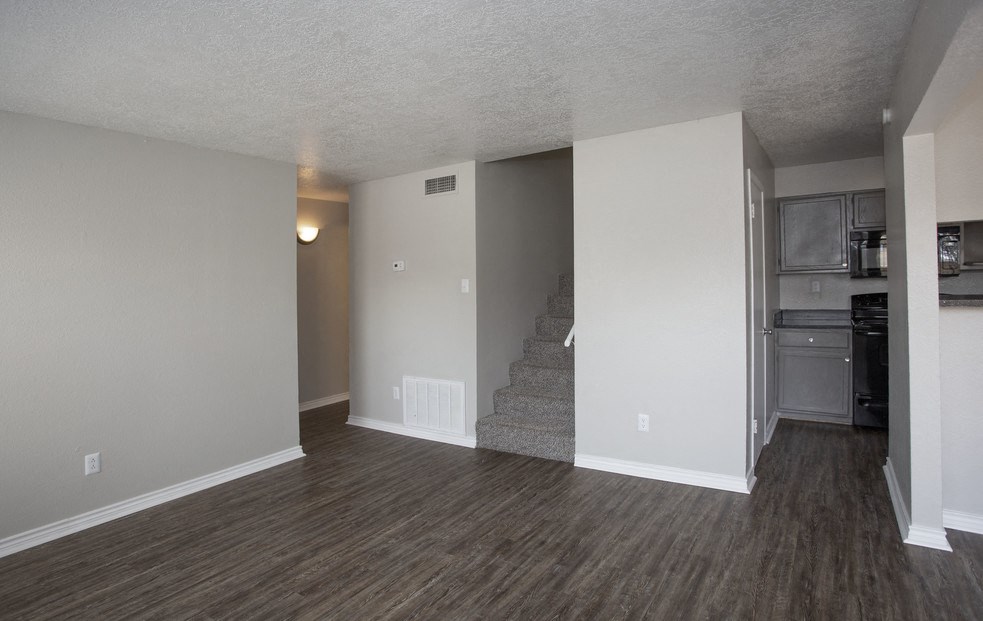 an empty living room with wood flooring and a staircase