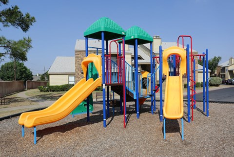 A playground with a yellow slide and a green roof.