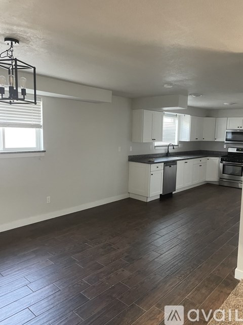 A kitchen with white cabinets and a wooden floor.