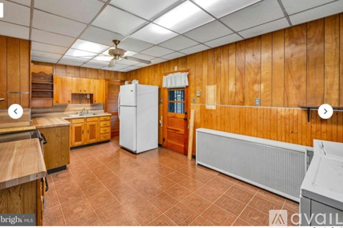 A kitchen with wooden walls and a white refrigerator.