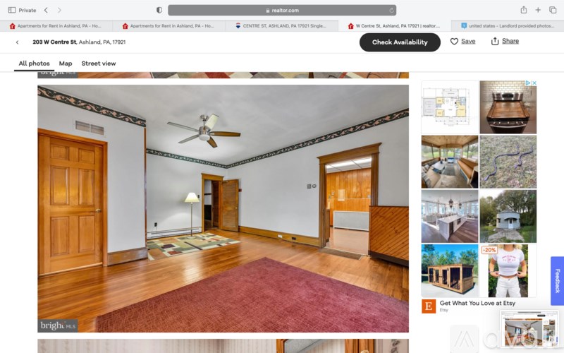 A room with wooden floors and a red rug is shown.