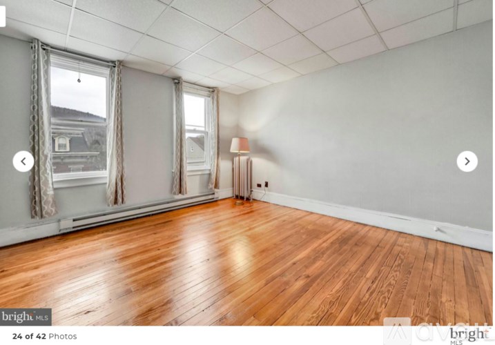 A room with wooden floors and two windows.