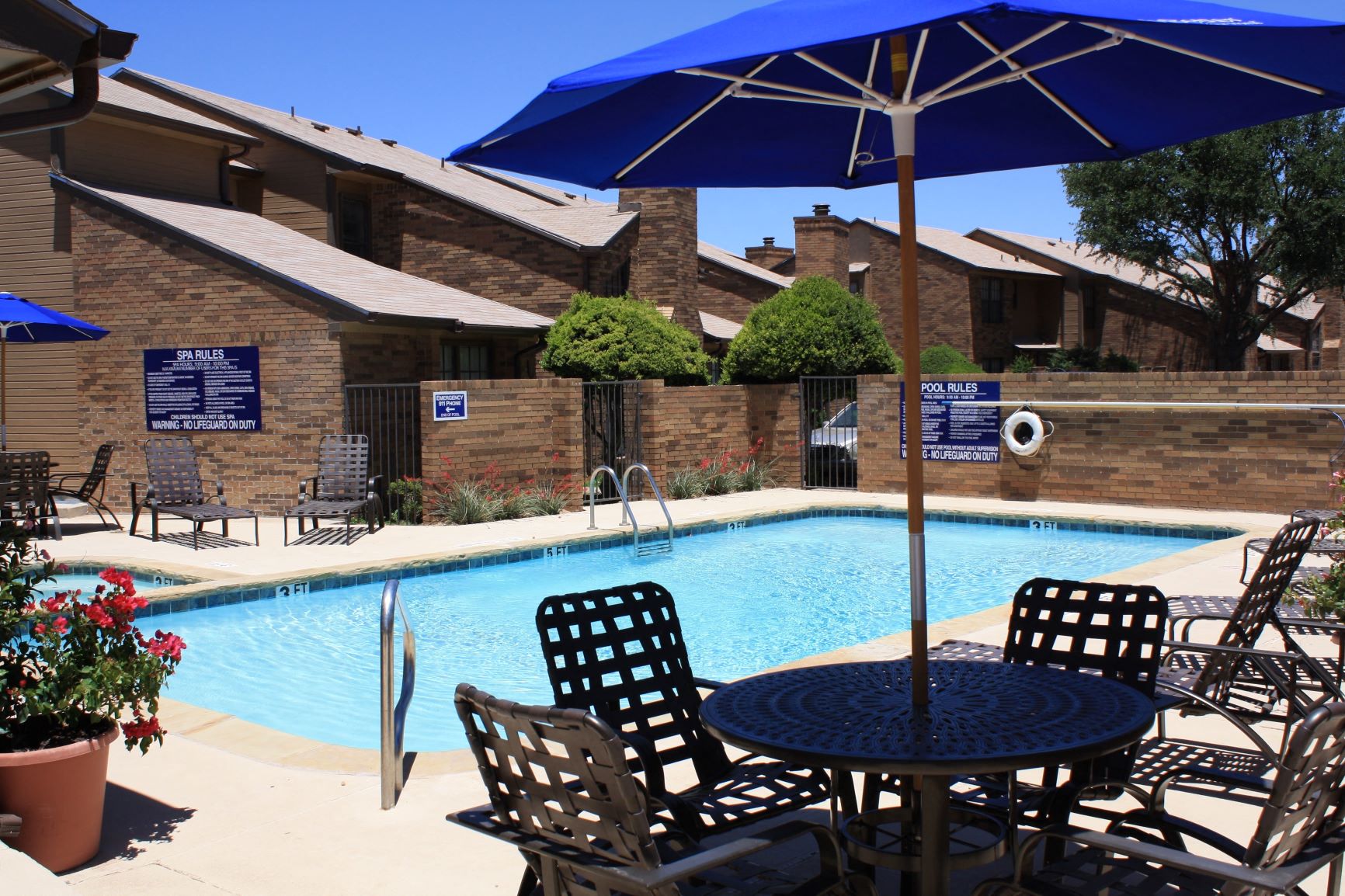 a swimming pool with a table and chairs under an umbrella
