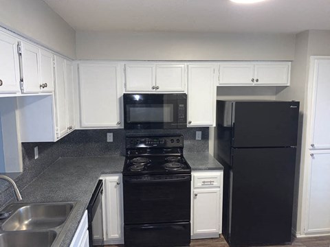 a kitchen with black appliances and white cabinets